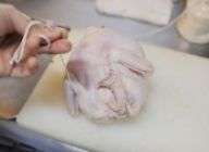 鶏の形を整え、タコ糸で両足を一回縛り、タコ糸をモモ肉のつけねを通し、ひっくり返して手羽の上でできるだけ固く縛る。