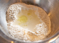 【piciの生地】ボウルに中力粉を入れて土手を作り、中央に水・ピュアオリーブオイルを注ぎ、塩を加えゆっくりとかき混ぜながらなじませる。